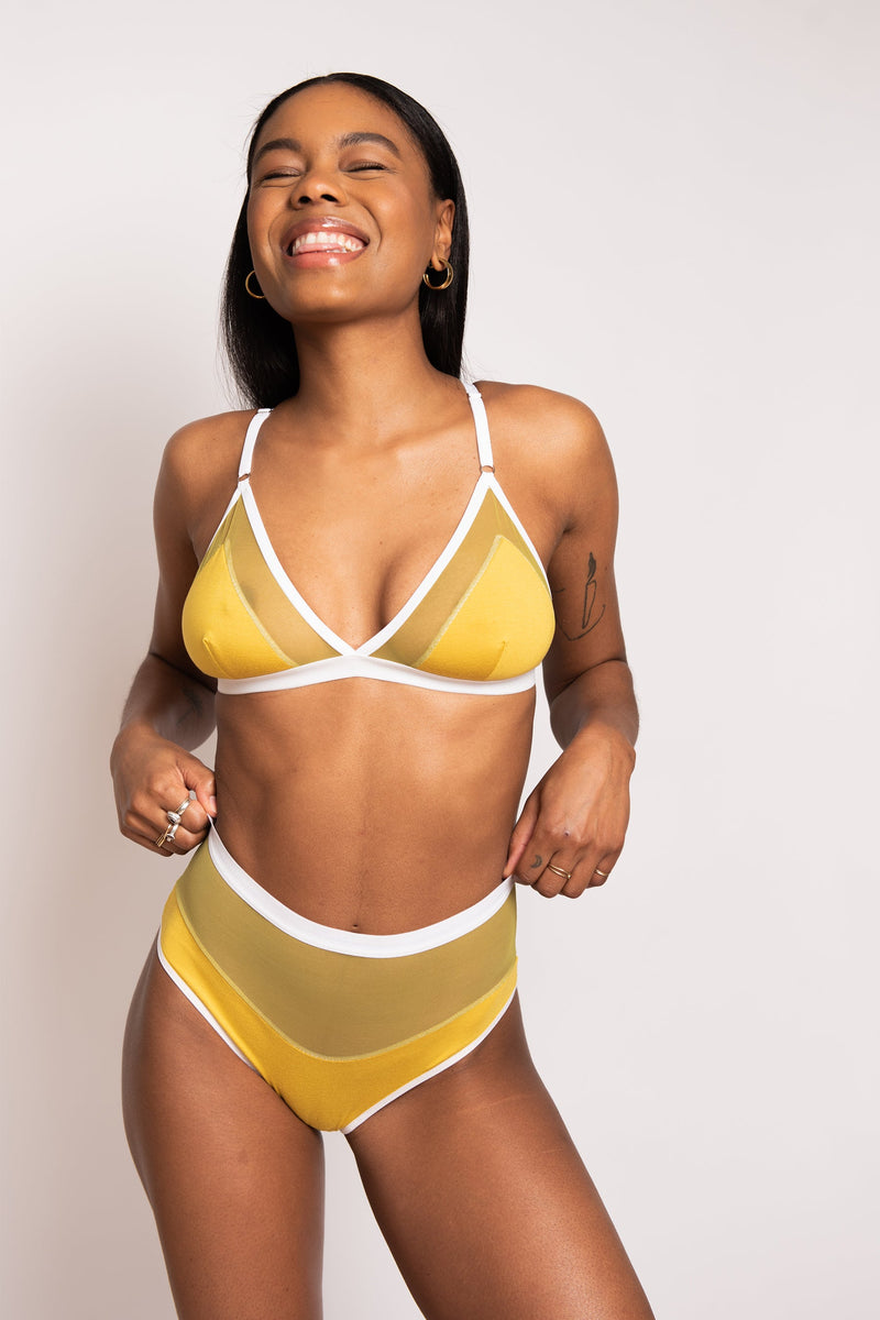 model smiling while wearing yellow bra and high waist bikini set